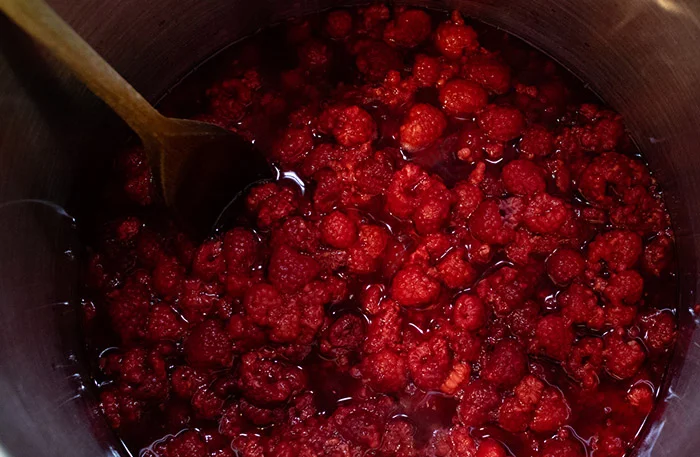 Raspberries just starting to boil in a large saucepan, which is stage 1 of this raspberry jam recipe. 