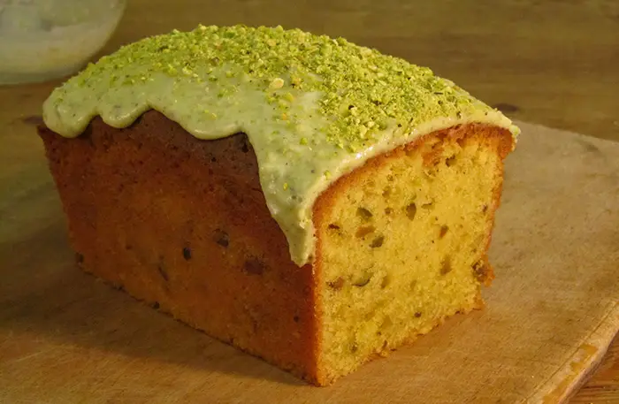 A Pistachio Loaf Cake which has been sliced at one end, revealing the moist looking inside section of the cake. 