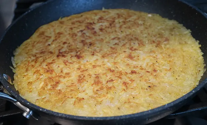 The hash browns cooking in the frying pan