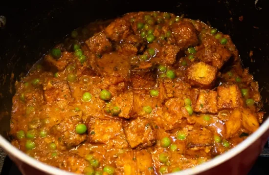 Mattar paneer – Sweet and spicy cheese and pea curry cooking in a saucepan