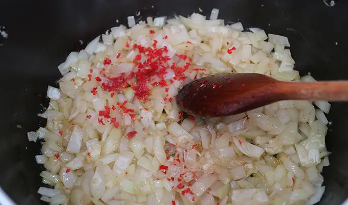 The chopped onion and chillies being fried in a large pan