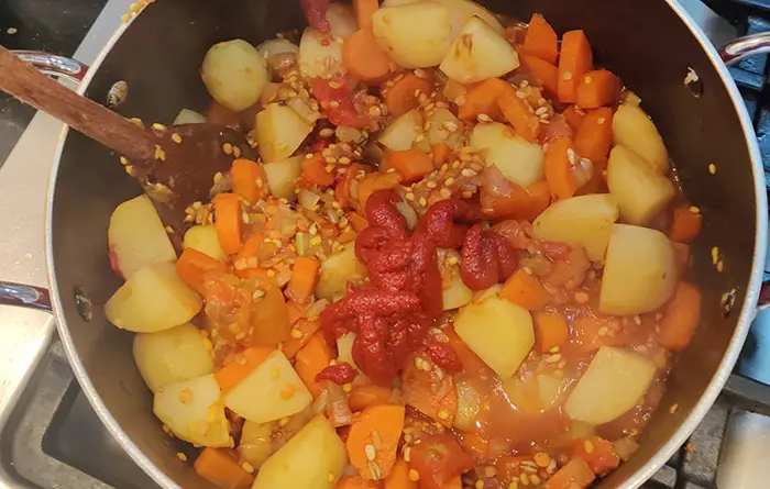 The early stages of the Barley and Vegetable Soup recipe cooking in a red saucepan